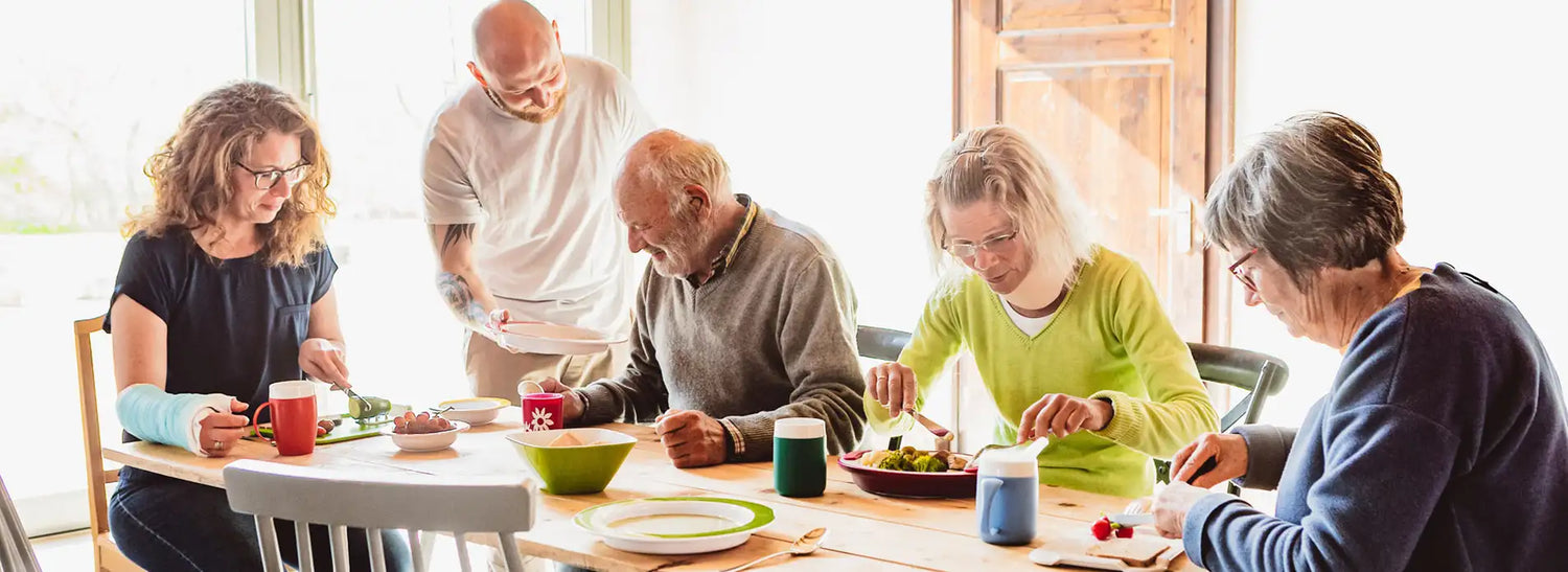 people enjoying a meal together with various disabilities and using plastic tableware