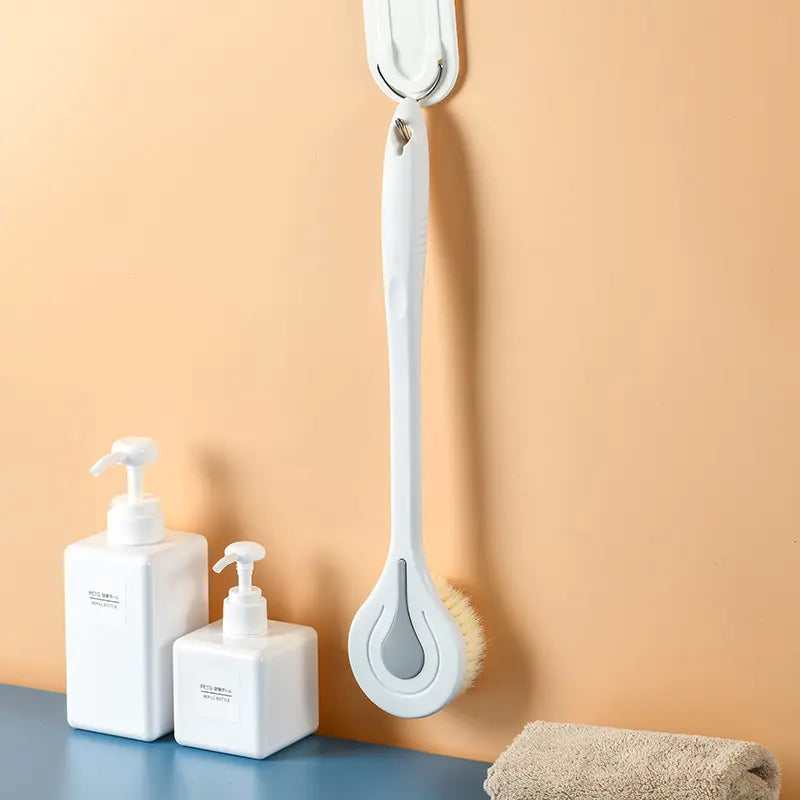 light grey long handled back scrubber hanging from wall in bathroom setting