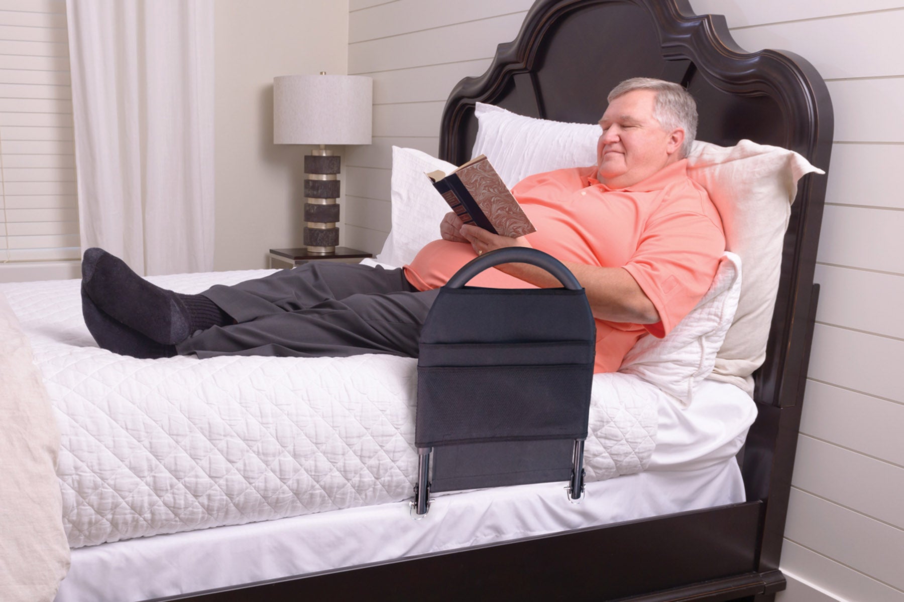 bed rail mounted to bed with person lying and reading on bed