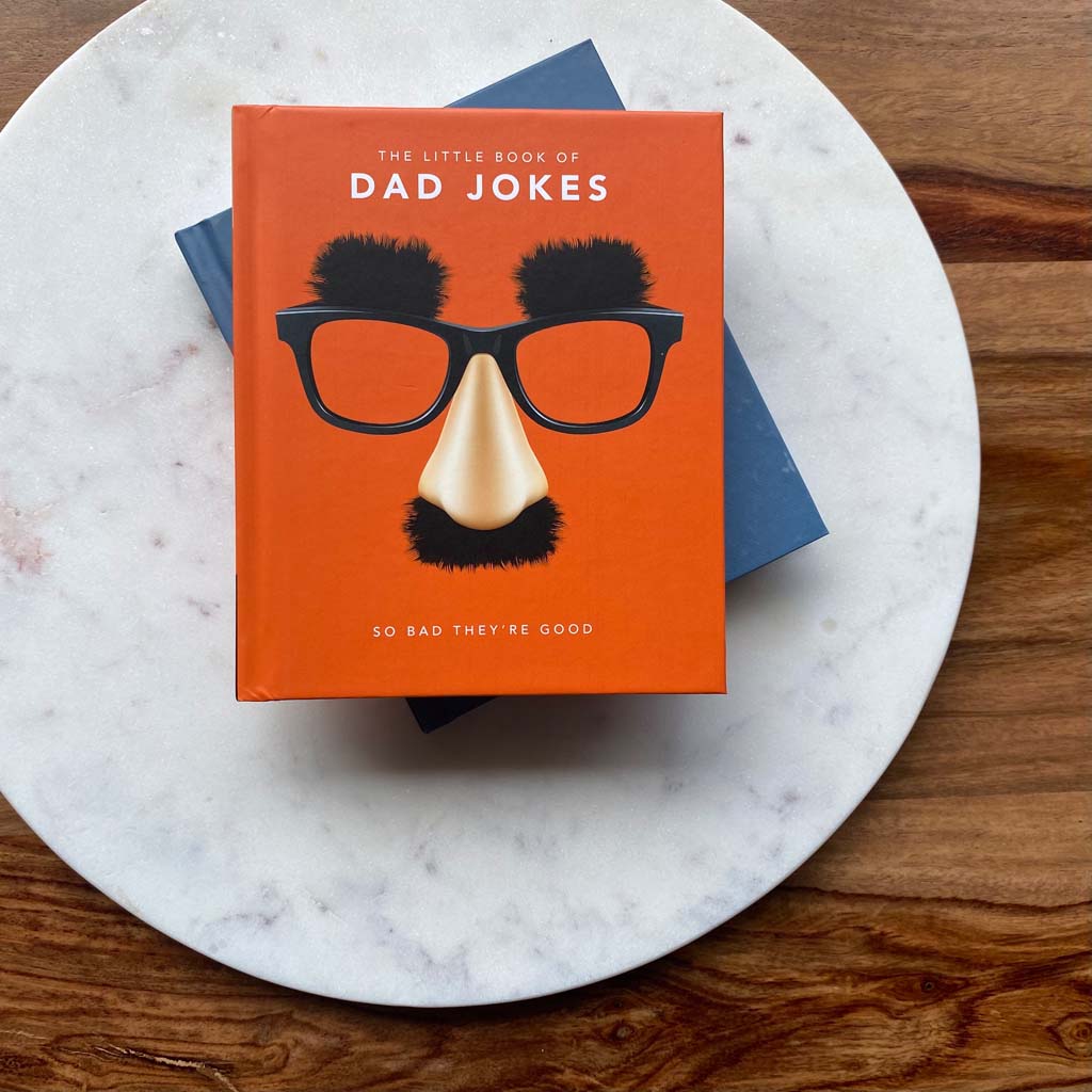 The Little Book of Dad Jokes Book top view on wooden table and marble board