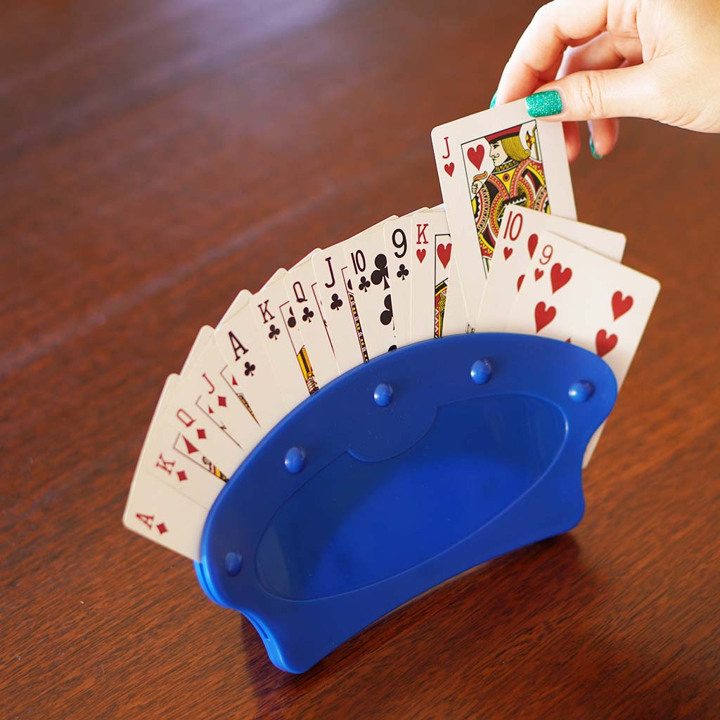 playing card holder on a table whilst one hand pulls one card out of it