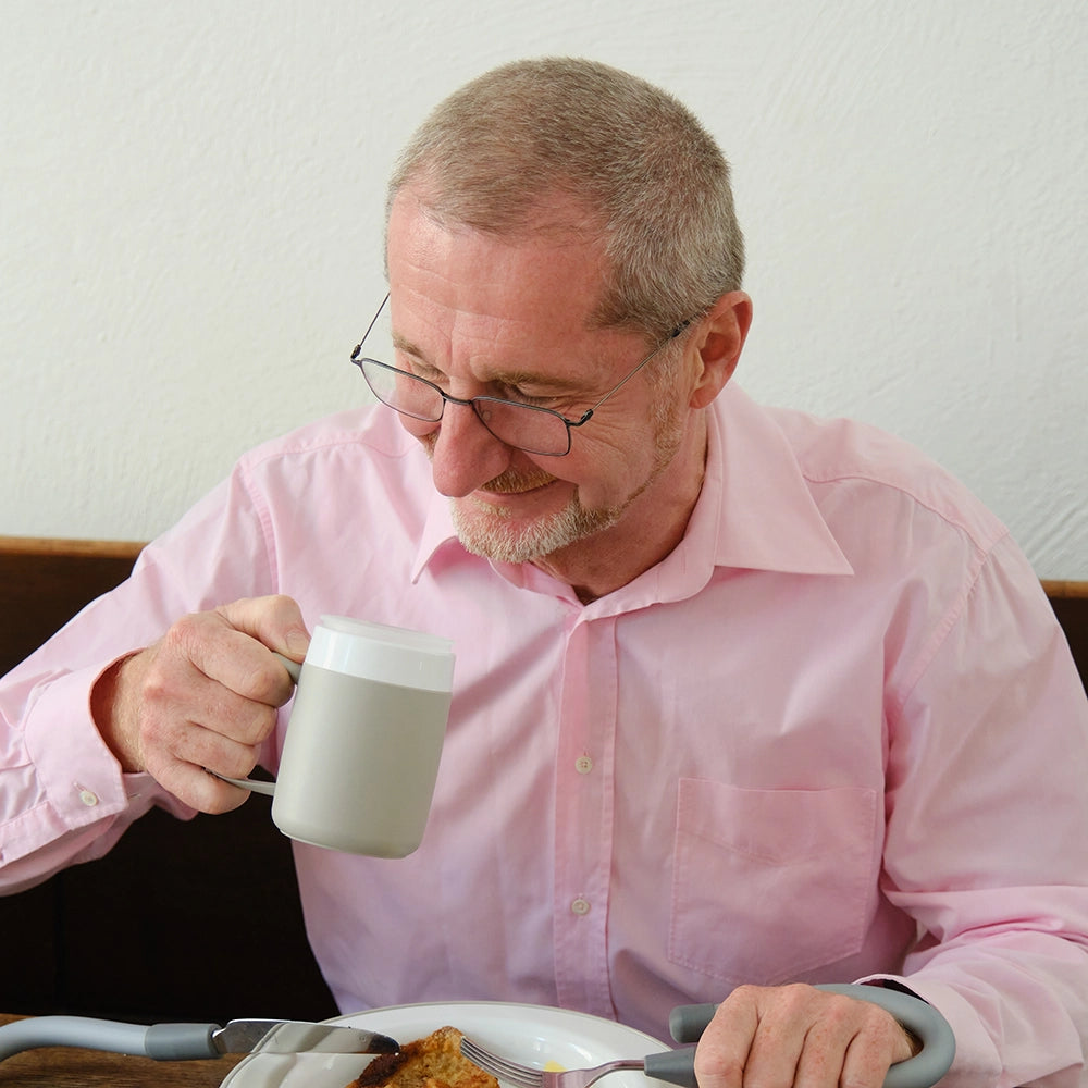 person drinking from plastic mug beaker at meal time