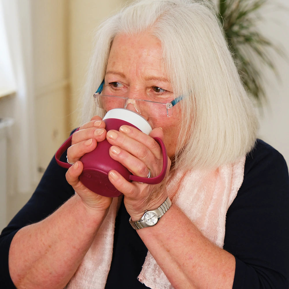 persona drinking from two handled plastic mug beaker
