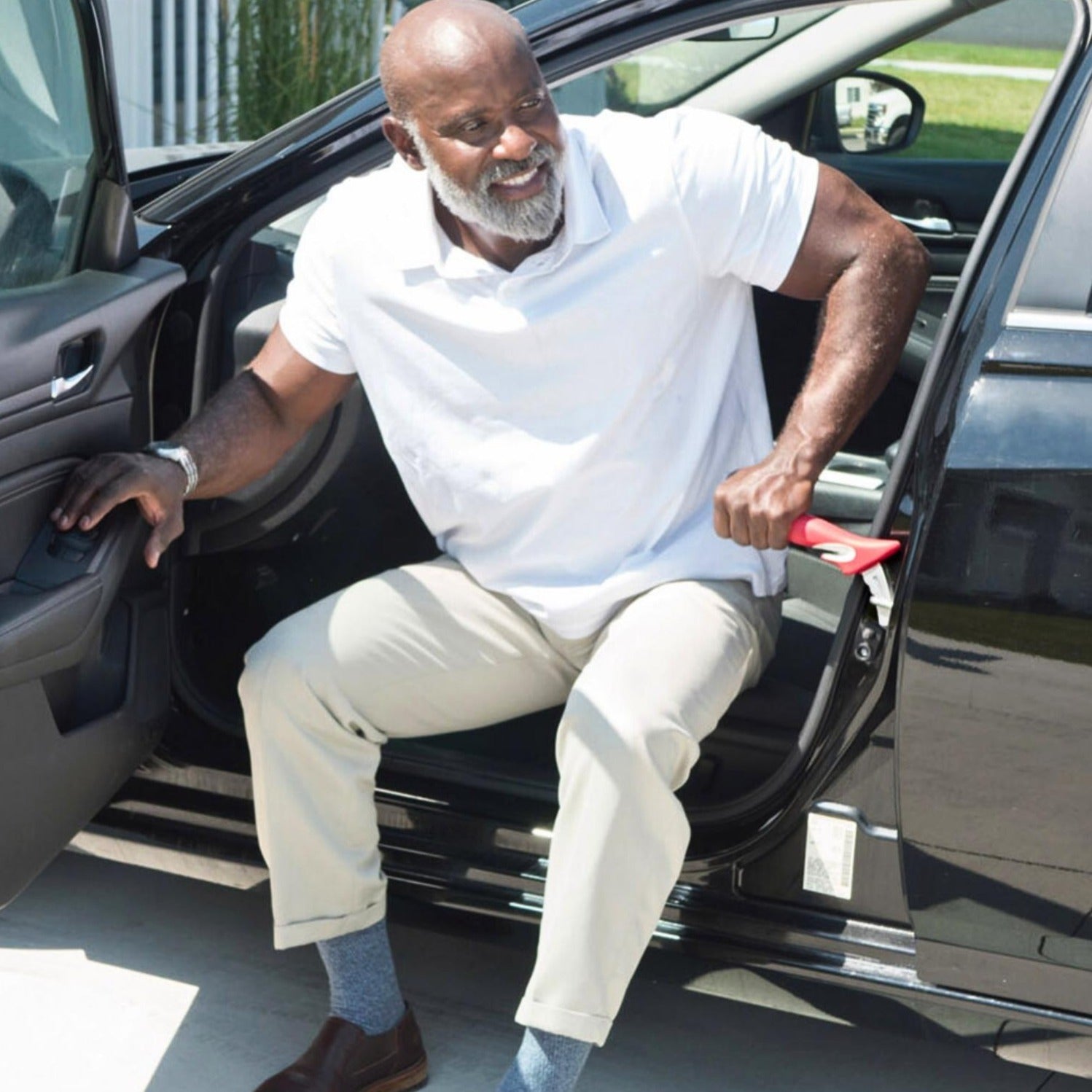 person using the handybar car transfer handle to get out of the car