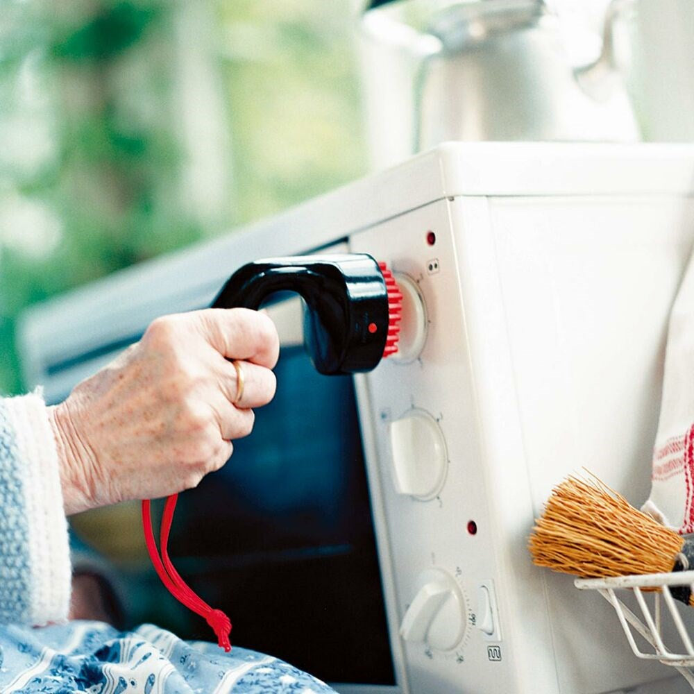 elderly person using universal handle and tap turner to turn dials