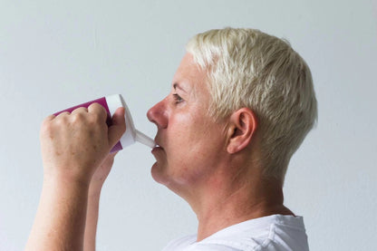 person drinking from plastic mug beaker with fitted spout lid