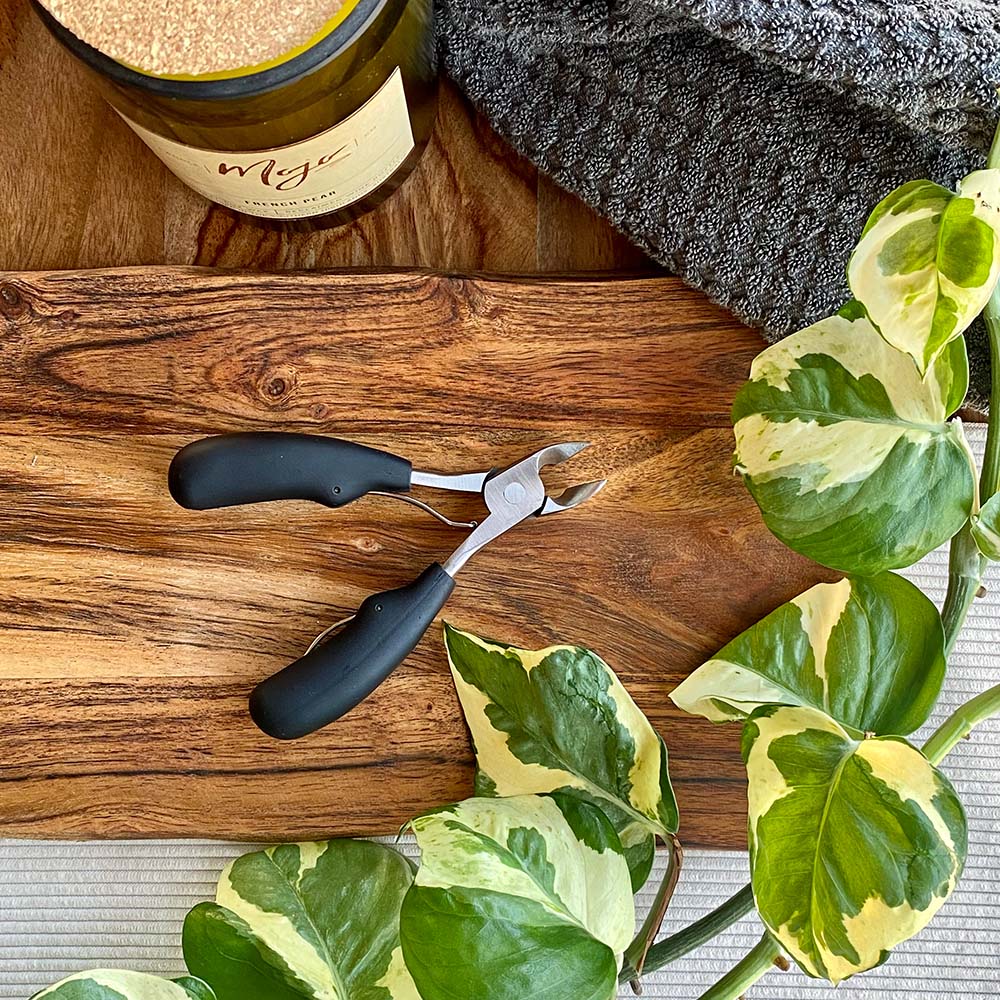 black thick handled nail clippers on wooden board