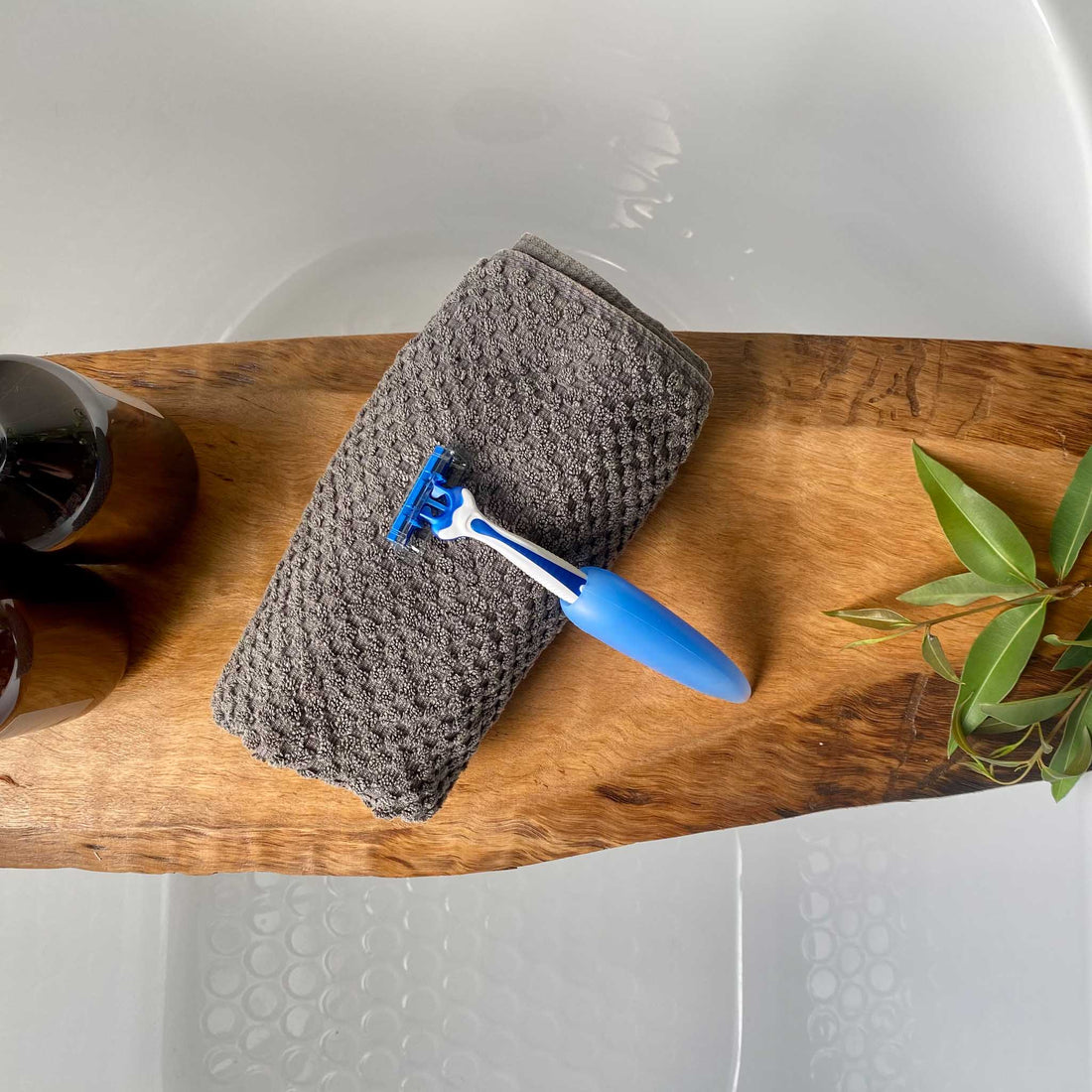 multipurpose grip holding razor resting on hand towel on a wooden bath rail