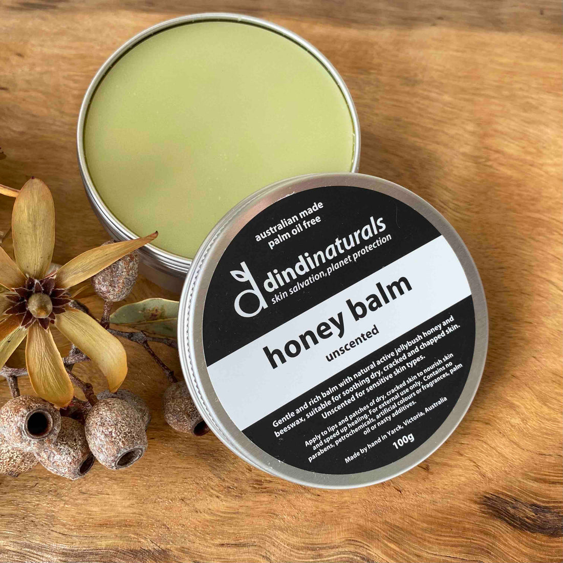 Dindi honey balm open tin with gum nuts on wooden base with