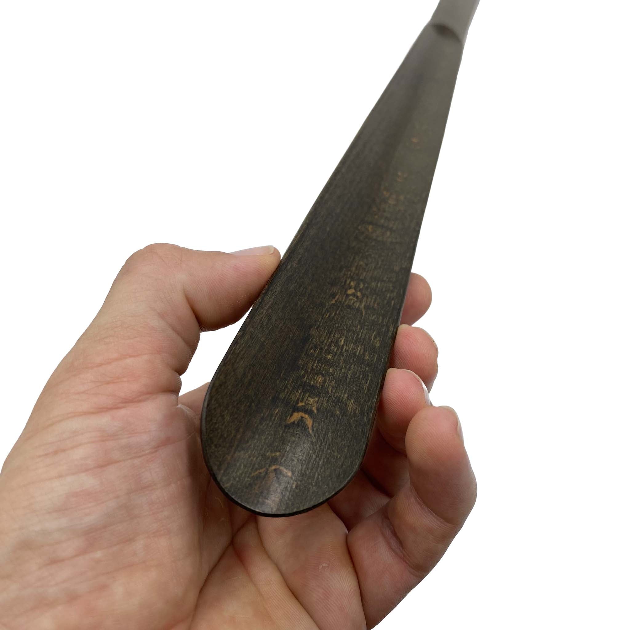 hand holding spoon of long wooden shoe horn