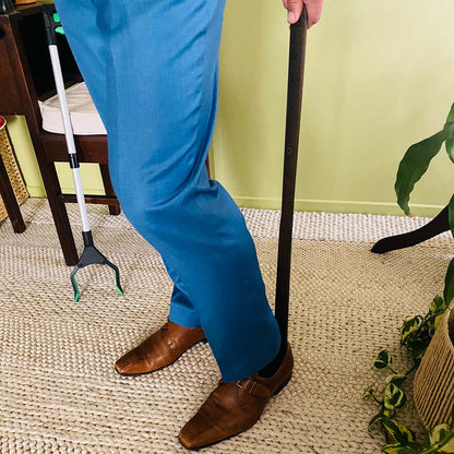 person using long wooden shoe horn to put shoes on