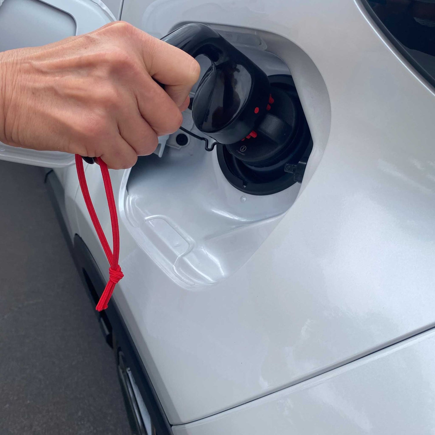 person using universal turner opening petrol cap of white car